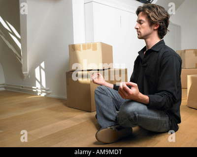 Man doing yoga with moving boxes around him. Stock Photo