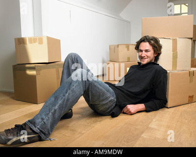 Man lying on floor smiling with moving boxes around him. Stock Photo