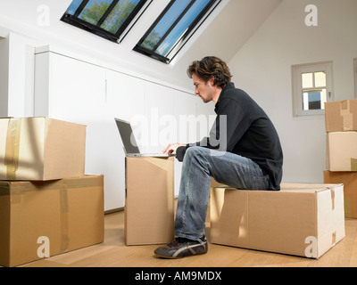 Man sitting with laptop on moving box. Stock Photo