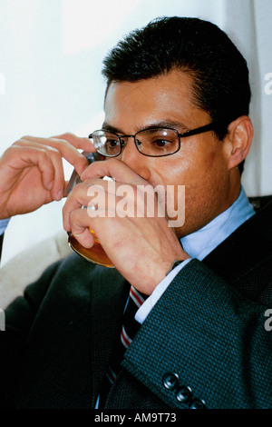 Portrait of a Businessman of Hispanic Ethnicity He is Holding a Drink Cocktail and Is Using a Cellular Telephone Stock Photo