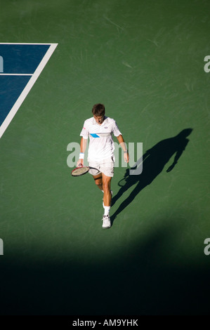 tennis player wearing white clothes walks behind serve line on green surface court 2005 Stock Photo