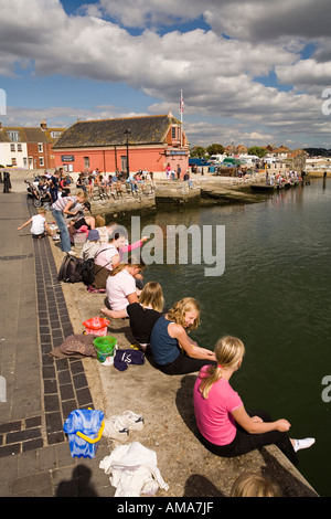 UK Dorset Poole Old Town families fishing for crabs from the quayside near the old lifeboat station Stock Photo