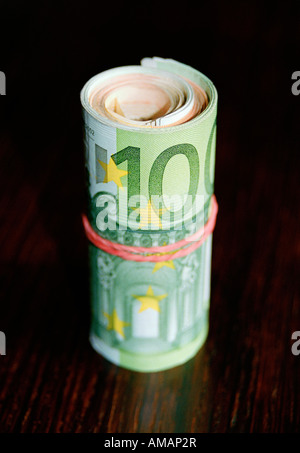 A roll of one hundred euro banknotes stands on a table on a light ...