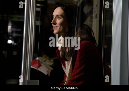 A woman sitting on a subway train smiling Stock Photo