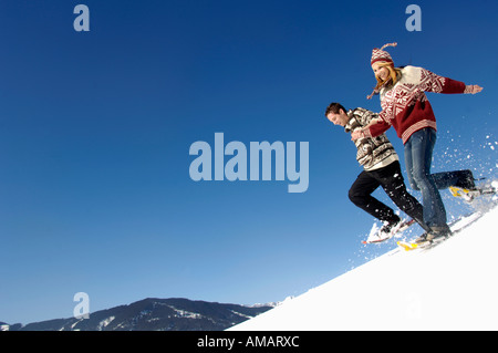 Young couple in snow, running downhill Stock Photo