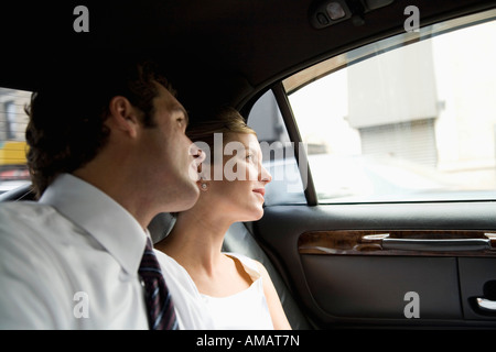 A bride and groom look out of a car window Stock Photo