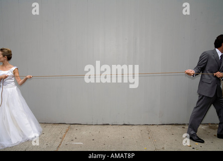 A bride and groom pulling a rope in different directions Stock Photo