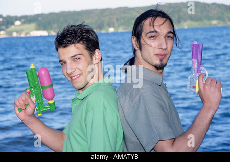 Two young men standing back to back, holding toy gun, portrait Stock Photo