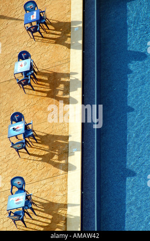 tables and  chairs seats set out alongside a swimming pool Stock Photo