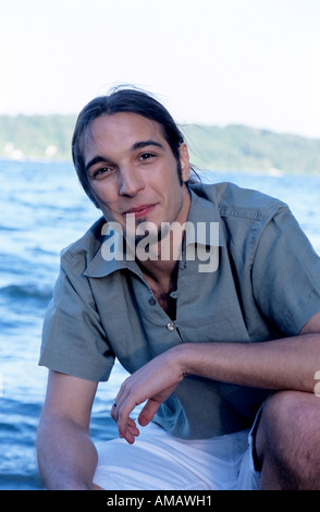 Portrait of young man crouching at beach, close-up Stock Photo