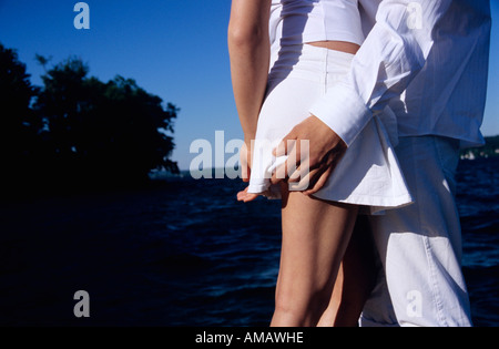 Young couple standing by lake, mid section, side view Stock Photo