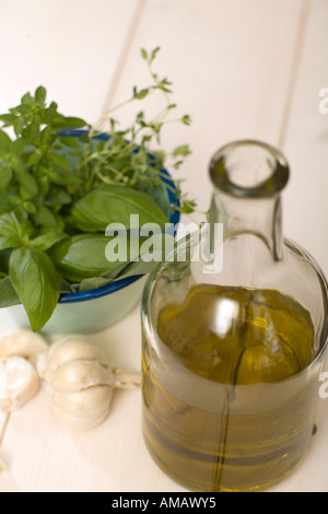 Herb-flavoured oil and various herbs in bowl Stock Photo