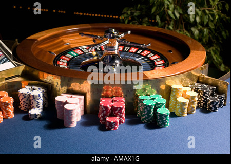 Roulette wheel with multiple stacks of gambling chips Stock Photo