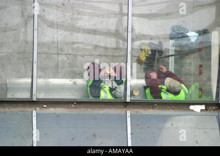 Overhead view of construction workers taking tea break in city centre bus shelter Stock Photo
