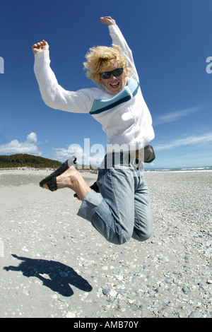 young fair-haired man jumping at the beach Stock Photo