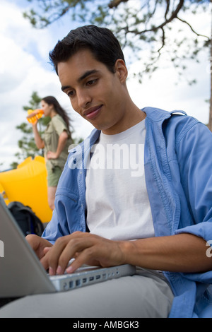young man at campsite using laptop computer Stock Photo