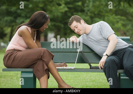 Mid adult couple sitting on a park bench and using laptops Stock Photo