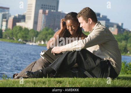 Mid adult couple sitting in a park reading a book, Boston, Massachusetts, USA Stock Photo
