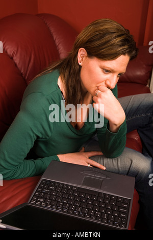 Woman looking worried while using a lap top computer. Stock Photo