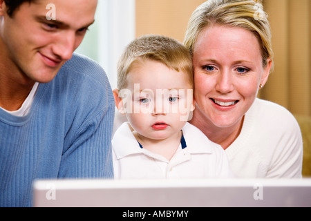 View of parents teaching their son to use a computer. Stock Photo
