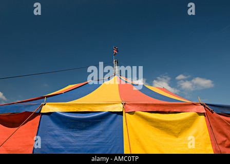 circus big top bright coloured with red yellow and blue with british flag on top Stock Photo