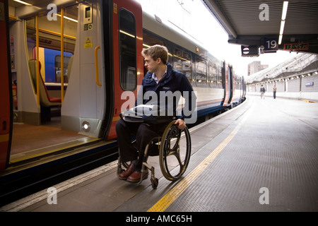 Disabled passenger waits at an open door on a train at railway station in London. UK. Presumably a ramp will arrive to allow safe boarding for person. Stock Photo