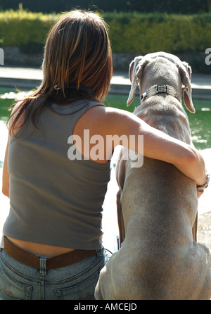 female sitting with weimaraner dog in garden Stock Photo