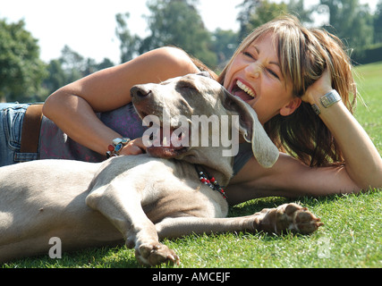 female laying with weimaraner dog on grass lawn Stock Photo