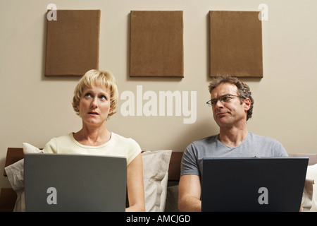 Couple Using Laptop Computers in Bed