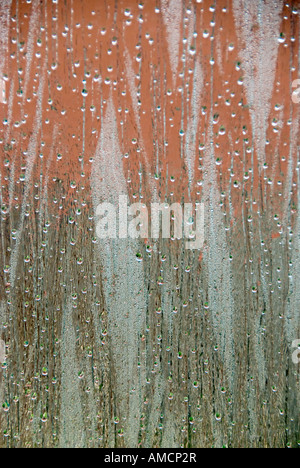 view looking out of a window focused on rain drops and condensation with a dominant green and red background Stock Photo