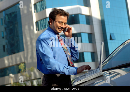 Indian Executive talking on mobile phone and working on computer, MR#637 Stock Photo