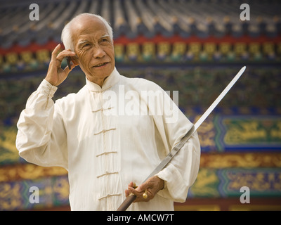 Man with sword talking on cell phone Stock Photo