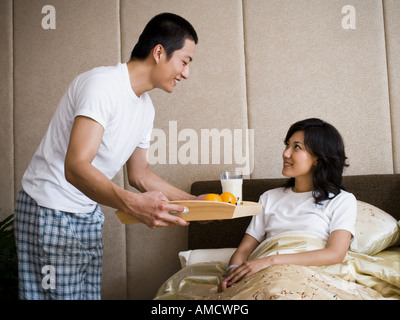 Man bringing woman breakfast in bed Stock Photo