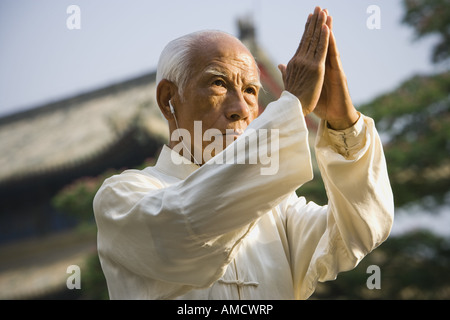 Man standing outdoors doing Kung Fu with ear buds and pagoda in background Stock Photo