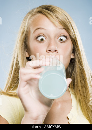 Girl drinking soda from bottle with eyes crossed Stock Photo