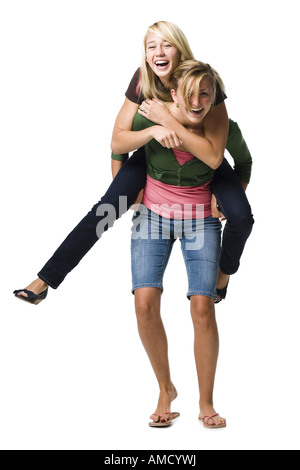 Two teenage girls laughing and giving piggy back ride Stock Photo