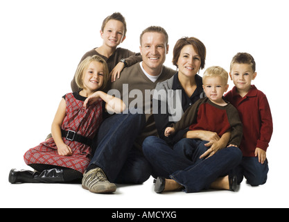 Family of six sitting cross legged posing and smiling Stock Photo