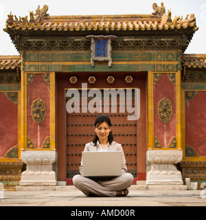 Businesswoman sitting cross legged outdoors with laptop Stock Photo