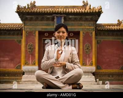 Businesswoman sitting cross legged outdoors meditating Stock Photo