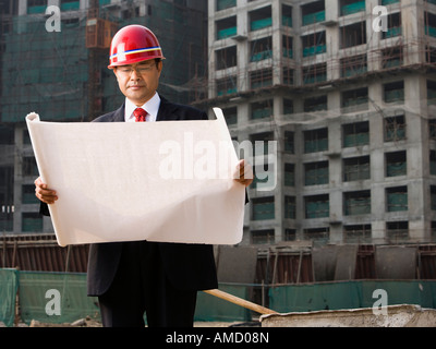 Construction site foreman with blueprints outdoors Stock Photo