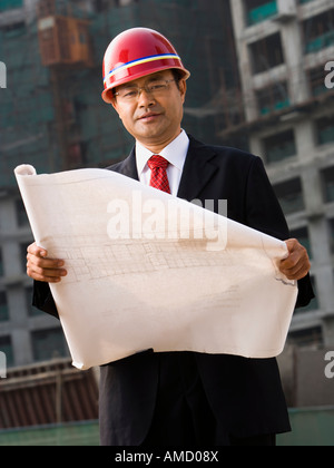 Construction site foreman with blueprints outdoors Stock Photo
