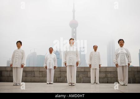 Group doing tai chi outdoors with city skyline in background Stock Photo