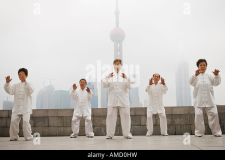 Group doing tai chi outdoors with city skyline in background Stock Photo