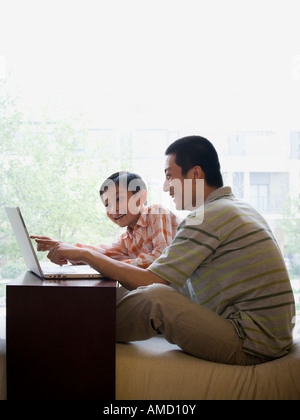 Man and boy sitting at computer Stock Photo