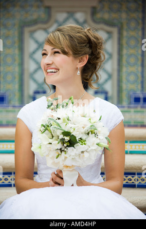 Bride sitting on steps with bouquet smiling Stock Photo - Alamy