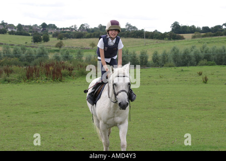 A young rider high in her saddle riding her pony. Stock Photo