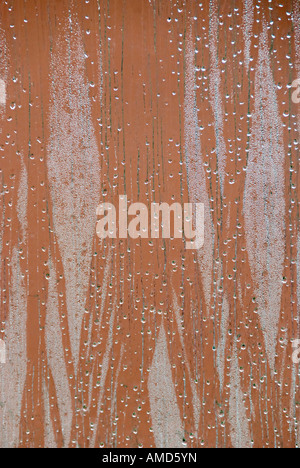 view looking out of a window focused on rain drops and condensation with a dominant green and red background Stock Photo