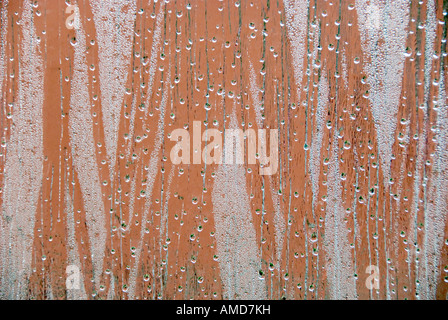 view looking out of a window focused on rain drops and condensation with a dominant green and red background Stock Photo