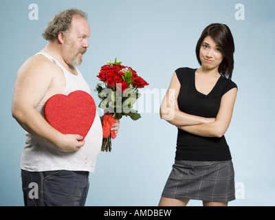 Disheveled man with heart box and red roses with disinterested woman Stock Photo