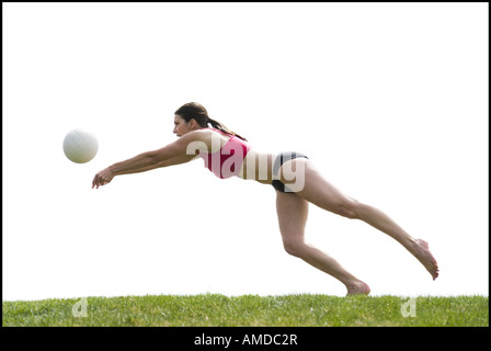 Woman in bikini playing volleyball outdoors on grass Stock Photo